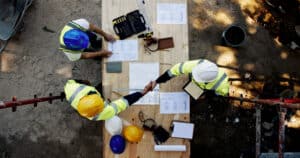 construction workers shaking hands over blueprints 2026 03 25 07 45 10 utc
